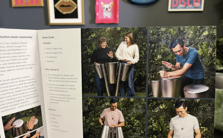 A brochure open to a page featuring images of people playing metal drums outdoors, surrounded by greenery. The left side presents text, whilst the right side displays four photos—similar to scenes from Outdoor Cooking Videos—of individuals enjoying the drums.